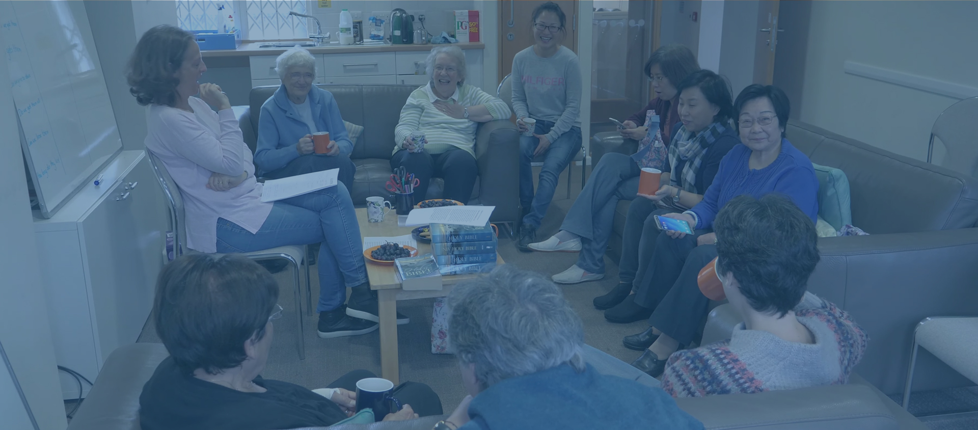 A group from church chatting over mugs of tea, with Bibles on the table